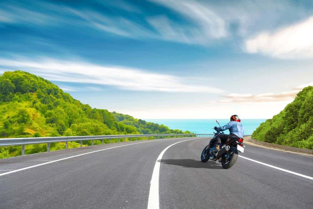 A person rides a motorcycle down a scenic coastal road